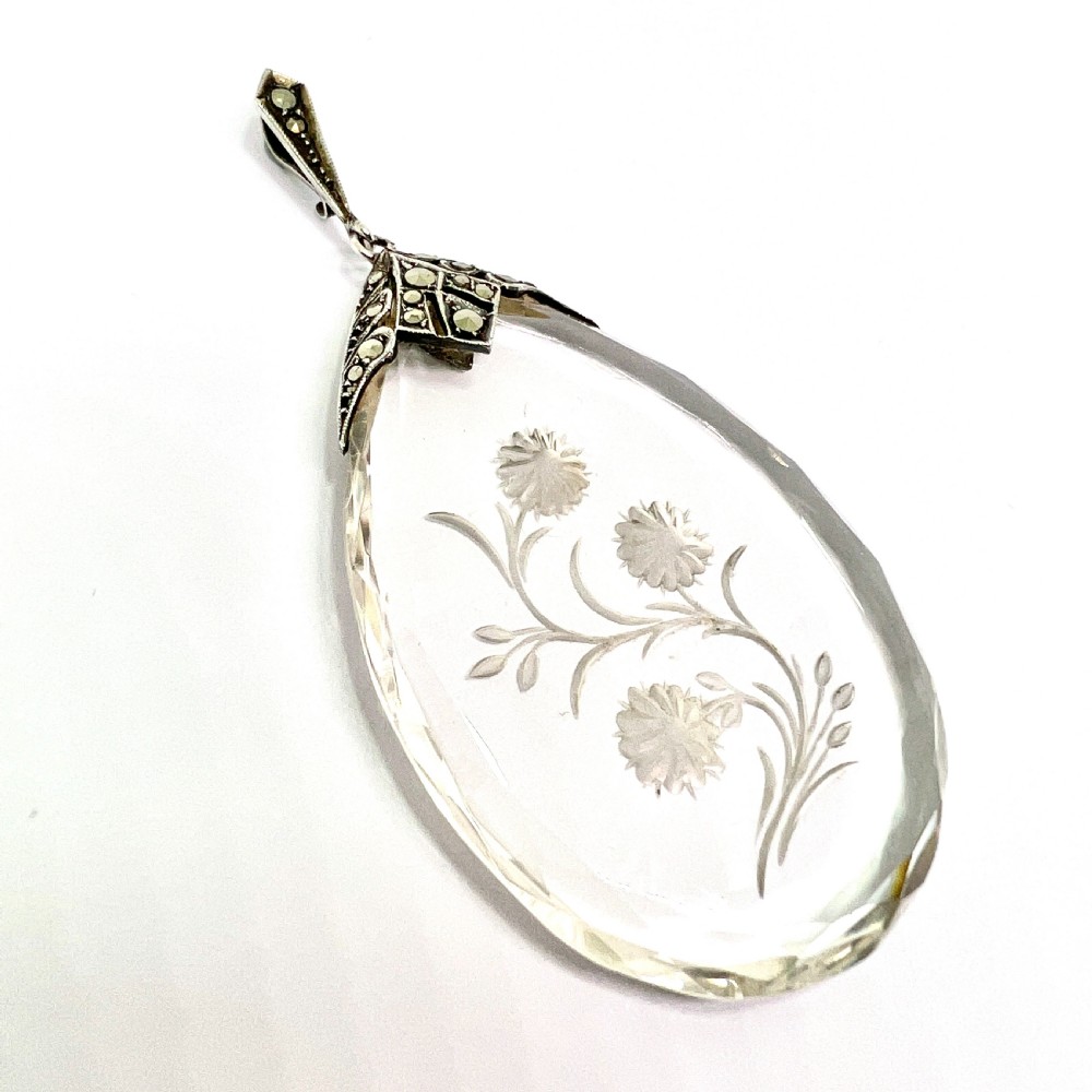 A clear glass teardrop pendant reverse-engraved with a floral motif, topped with a silver decorative cap set with faceted marcasite stones. View V