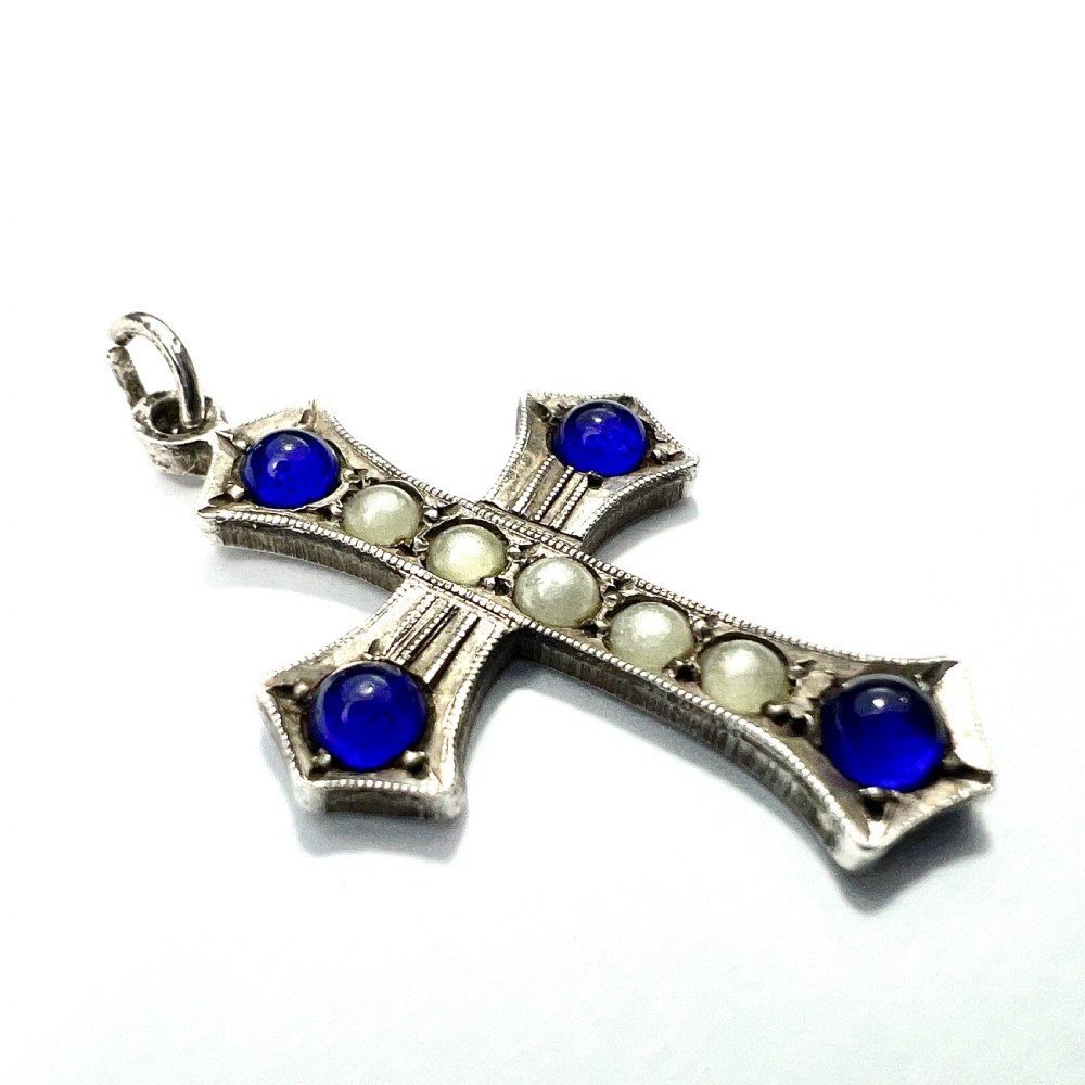 An antique sterling silver cross pendant set with blue paste cabochons and central white pearls against a white background. View II
