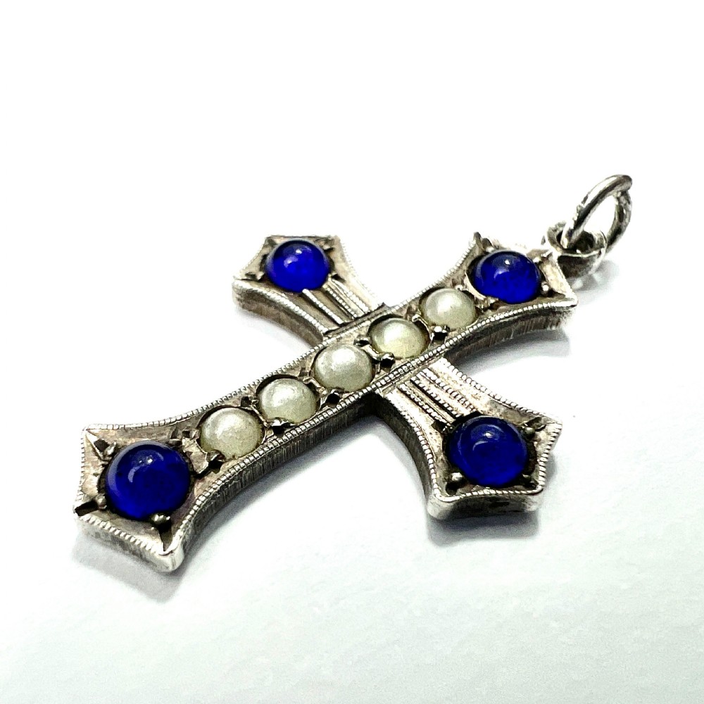 An antique sterling silver cross pendant set with blue paste cabochons and central white pearls against a white background. View III