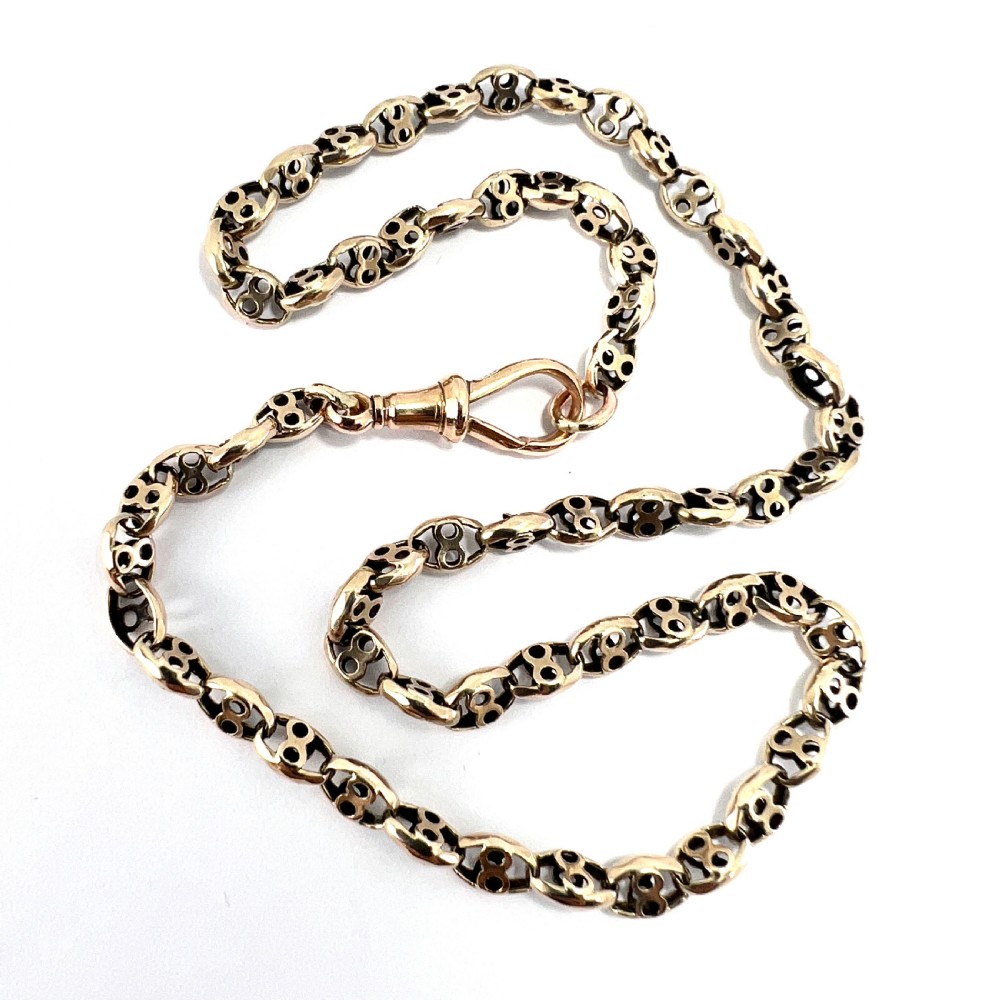 A coiled 9ct yellow gold Victorian fancy link albert chain featuring patterned open links and an attached swivel clip.