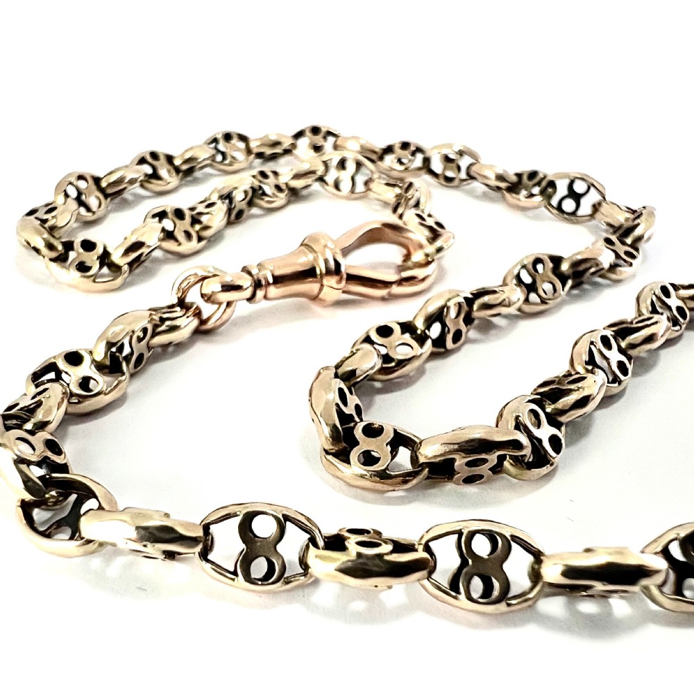 A coiled 9ct yellow gold Victorian fancy link albert chain featuring patterned open links and an attached swivel clip. View II