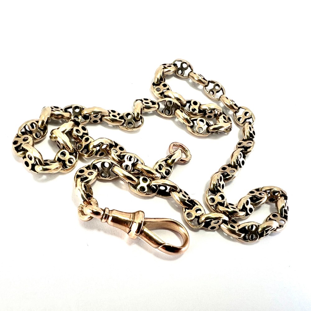 A coiled 9ct yellow gold Victorian fancy link albert chain featuring patterned open links and an attached swivel clip. View III