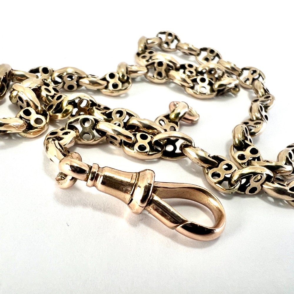 A coiled 9ct yellow gold Victorian fancy link albert chain featuring patterned open links and an attached swivel clip. View IV