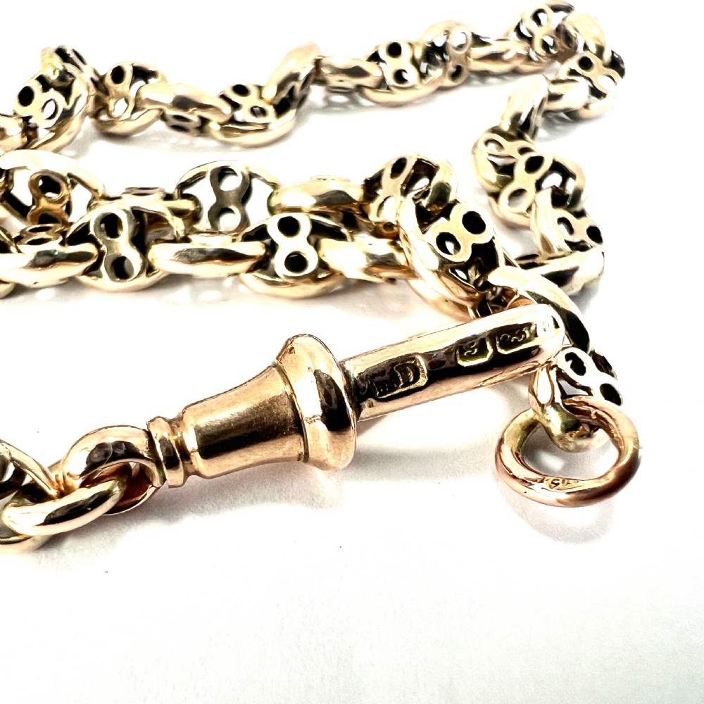 A coiled 9ct yellow gold Victorian fancy link albert chain featuring patterned open links and an attached swivel clip. View V
