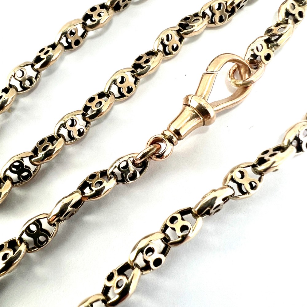 A coiled 9ct yellow gold Victorian fancy link albert chain featuring patterned open links and an attached swivel clip. View VI