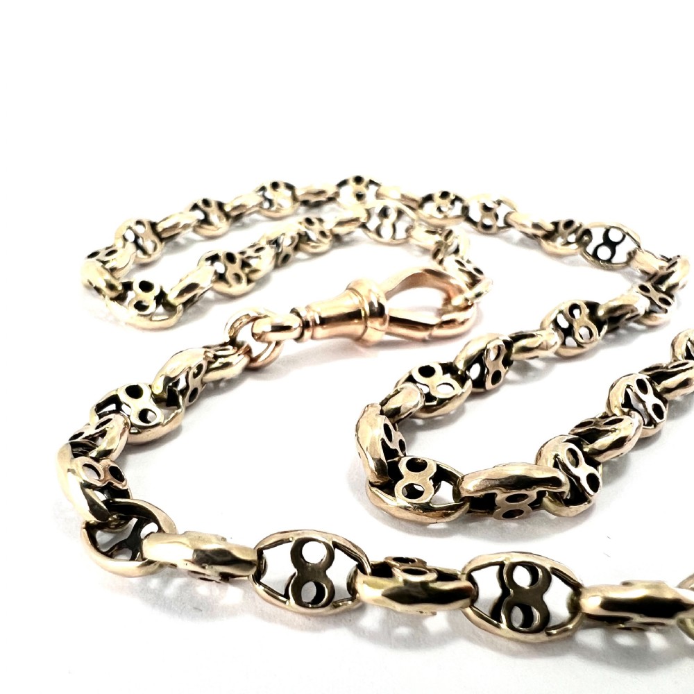 A coiled 9ct yellow gold Victorian fancy link albert chain featuring patterned open links and an attached swivel clip. View VII