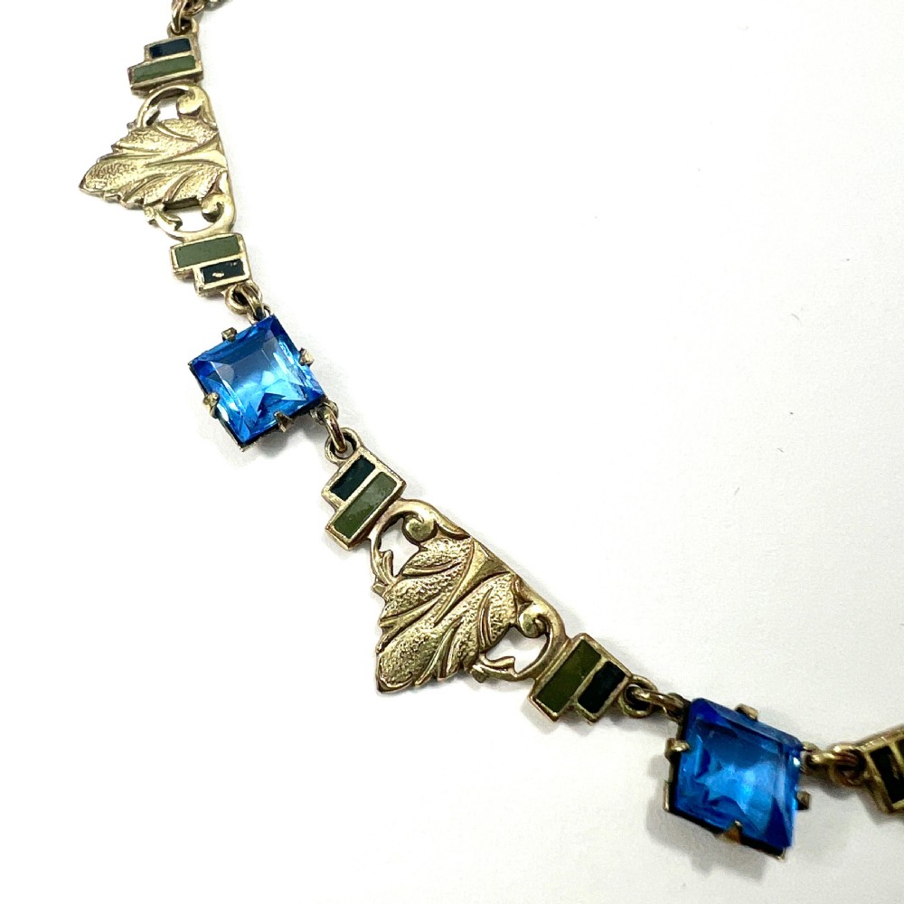 An art deco rolled gold necklace featuring square blue paste stones, leaf motifs, and dark enamel accents on a white background. View II