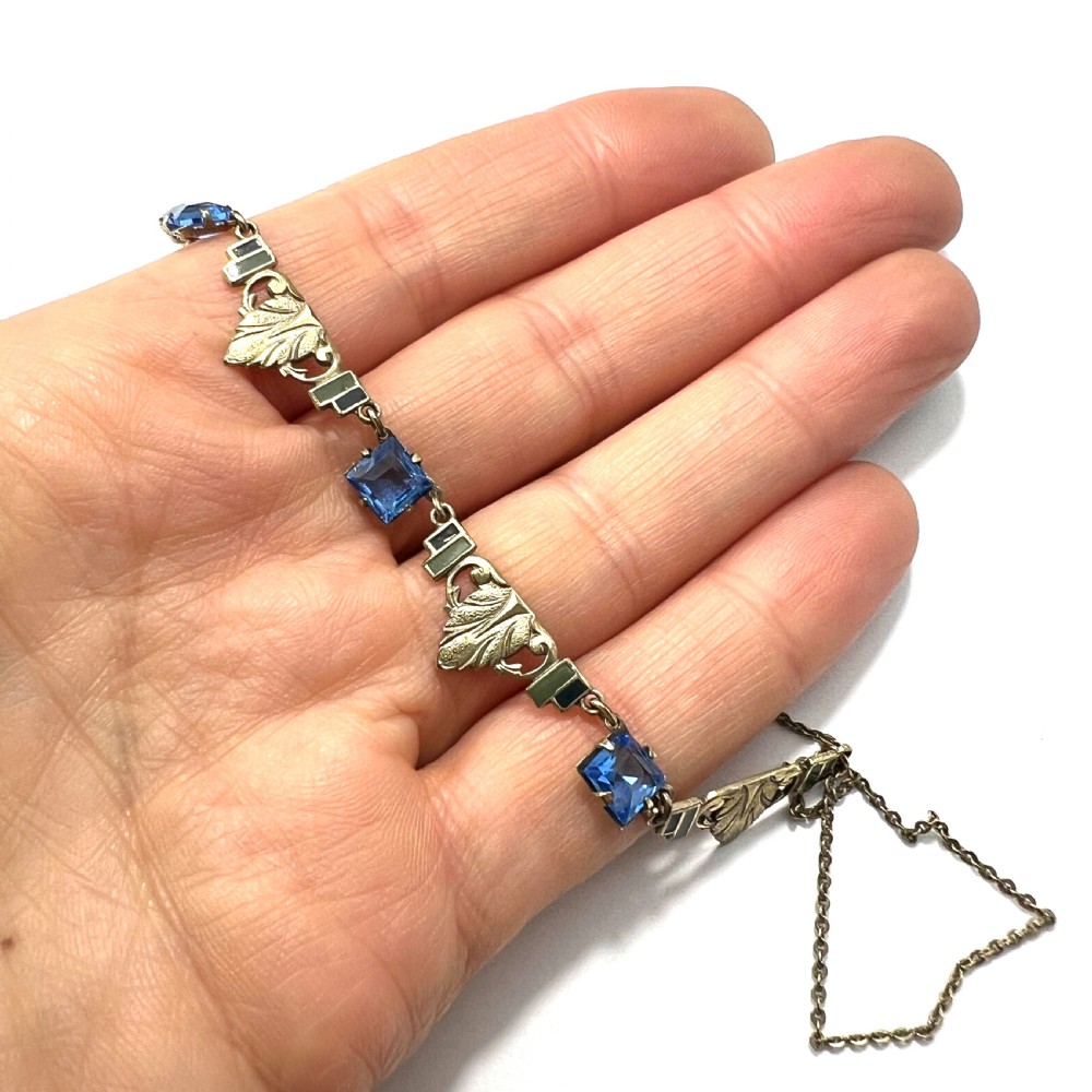 An art deco rolled gold necklace featuring square blue paste stones, leaf motifs, and dark enamel accents on a white background. View VIII