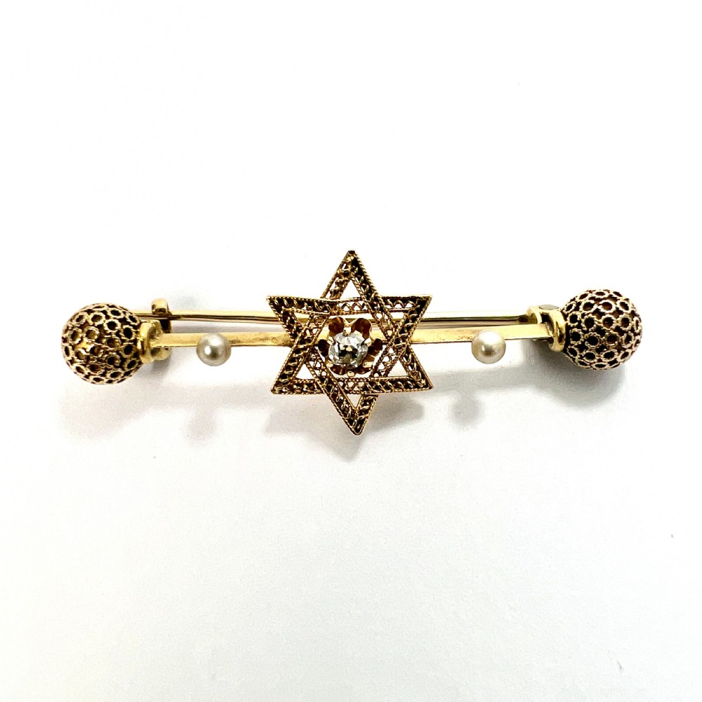 An 18ct yellow gold bar brooch featuring a central filigree Star of David set with a diamond, flanked by two pearls and spherical openwork end beads. View II