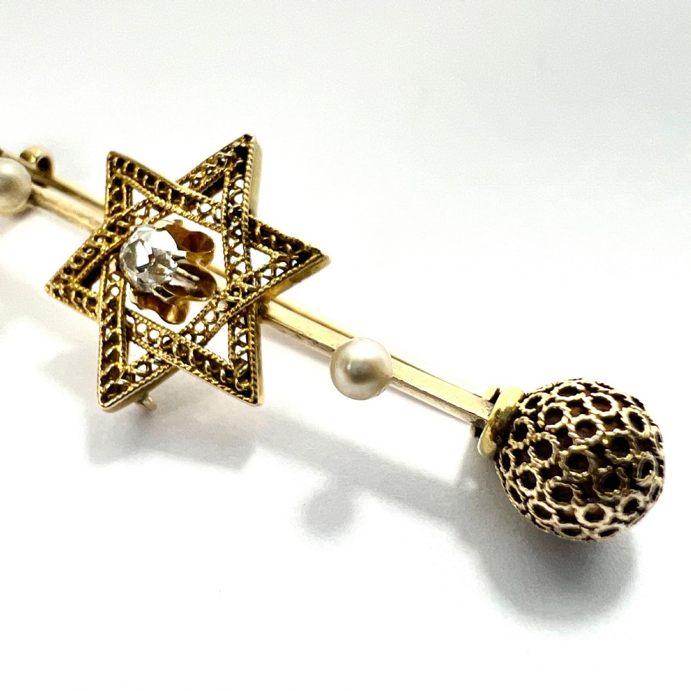 An 18ct yellow gold bar brooch featuring a central filigree Star of David set with a diamond, flanked by two pearls and spherical openwork end beads. View III