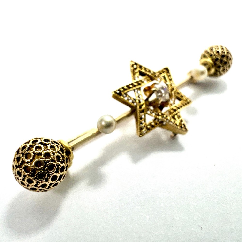 An 18ct yellow gold bar brooch featuring a central filigree Star of David set with a diamond, flanked by two pearls and spherical openwork end beads. View IV