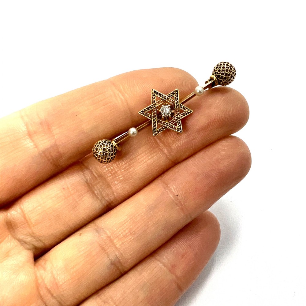 An 18ct yellow gold bar brooch featuring a central filigree Star of David set with a diamond, flanked by two pearls and spherical openwork end beads. View VIII