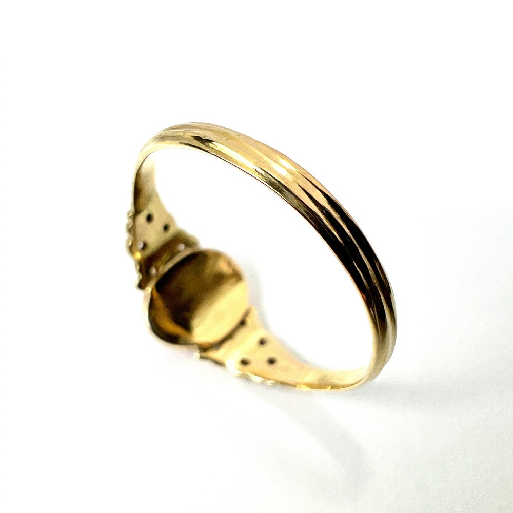 An antique gold ring featuring a central oval carved red coral cameo depicting a classical profile with decorative scrollwork shoulders. View VI
