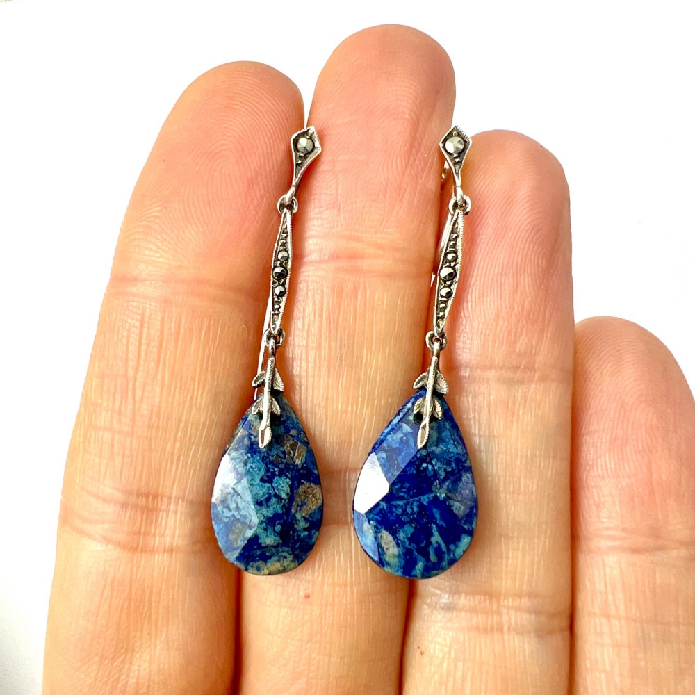 A pair of Art Deco silver screwback drop earrings featuring faceted blue teardrop stones suspended from linear marcasite-set bars. View V