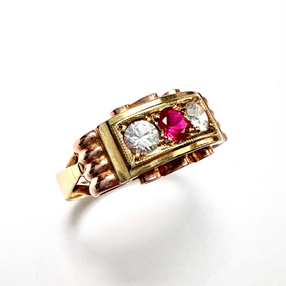 A vintage 14ct yellow and rose gold ring featuring a central red ruby paste stone flanked by two clear stones in a rectangular box setting with scrollwork shoulders. View III