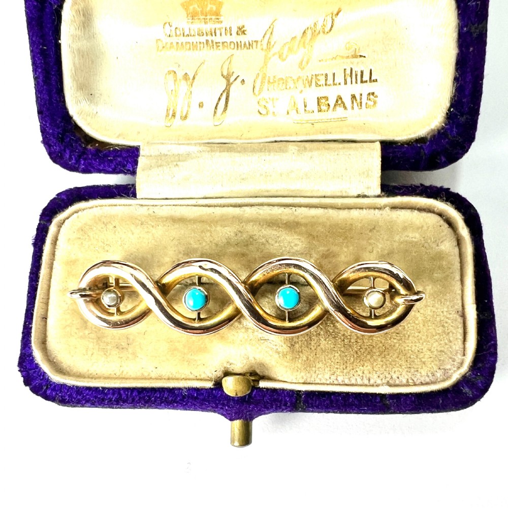 A late Victorian 15ct yellow gold bar brooch featuring intertwined wire loops set with central turquoise cabochons and outer pearls.