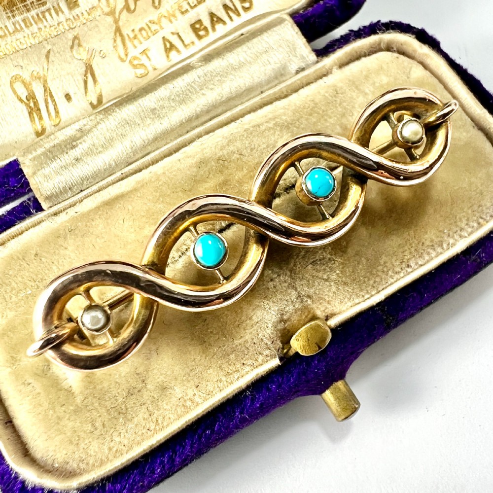 A late Victorian 15ct yellow gold bar brooch featuring intertwined wire loops set with central turquoise cabochons and outer pearls. View II