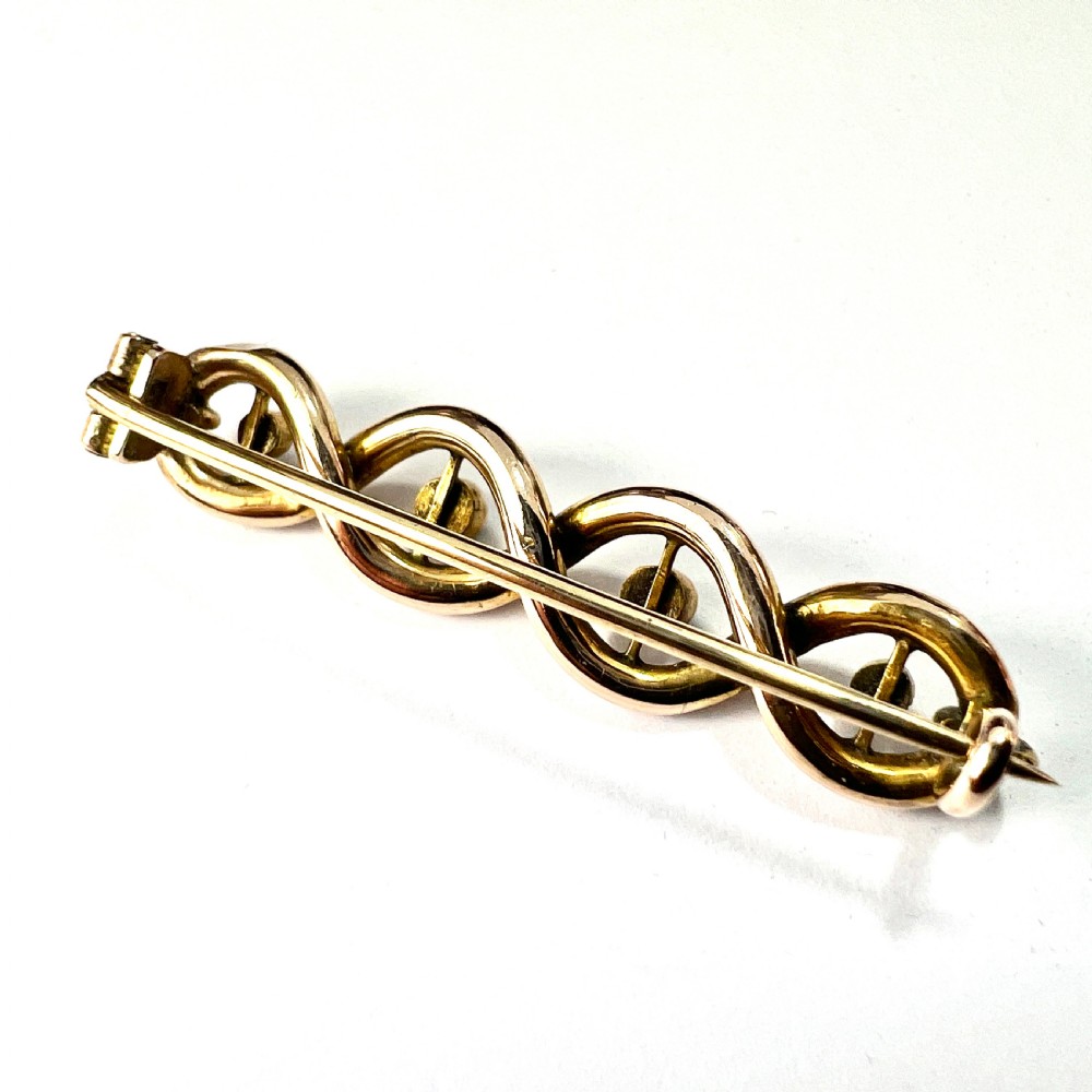 A late Victorian 15ct yellow gold bar brooch featuring intertwined wire loops set with central turquoise cabochons and outer pearls. View III