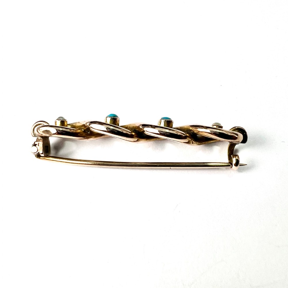 A late Victorian 15ct yellow gold bar brooch featuring intertwined wire loops set with central turquoise cabochons and outer pearls. View V