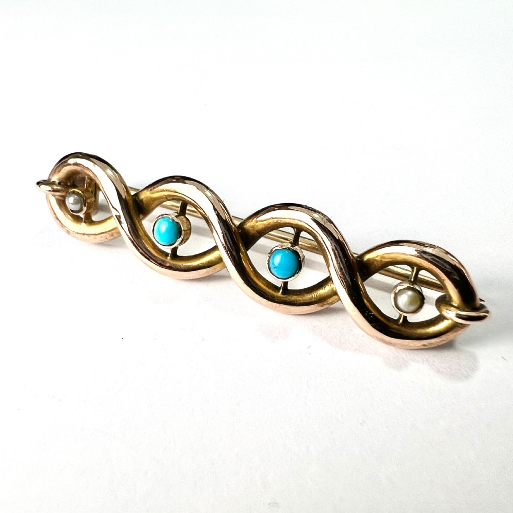 A late Victorian 15ct yellow gold bar brooch featuring intertwined wire loops set with central turquoise cabochons and outer pearls. View VI