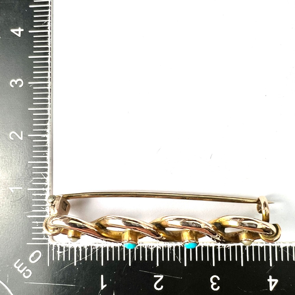 A late Victorian 15ct yellow gold bar brooch featuring intertwined wire loops set with central turquoise cabochons and outer pearls. View VII