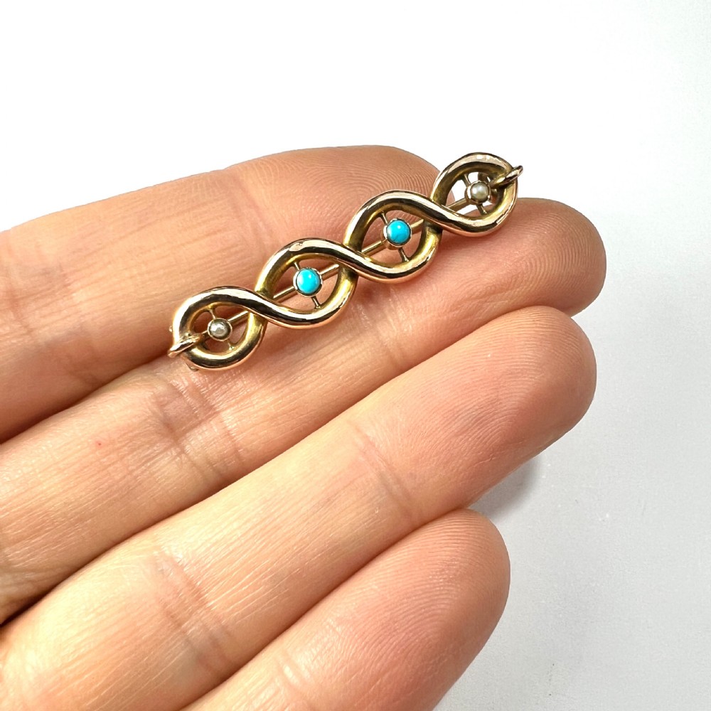 A late Victorian 15ct yellow gold bar brooch featuring intertwined wire loops set with central turquoise cabochons and outer pearls. View VIII