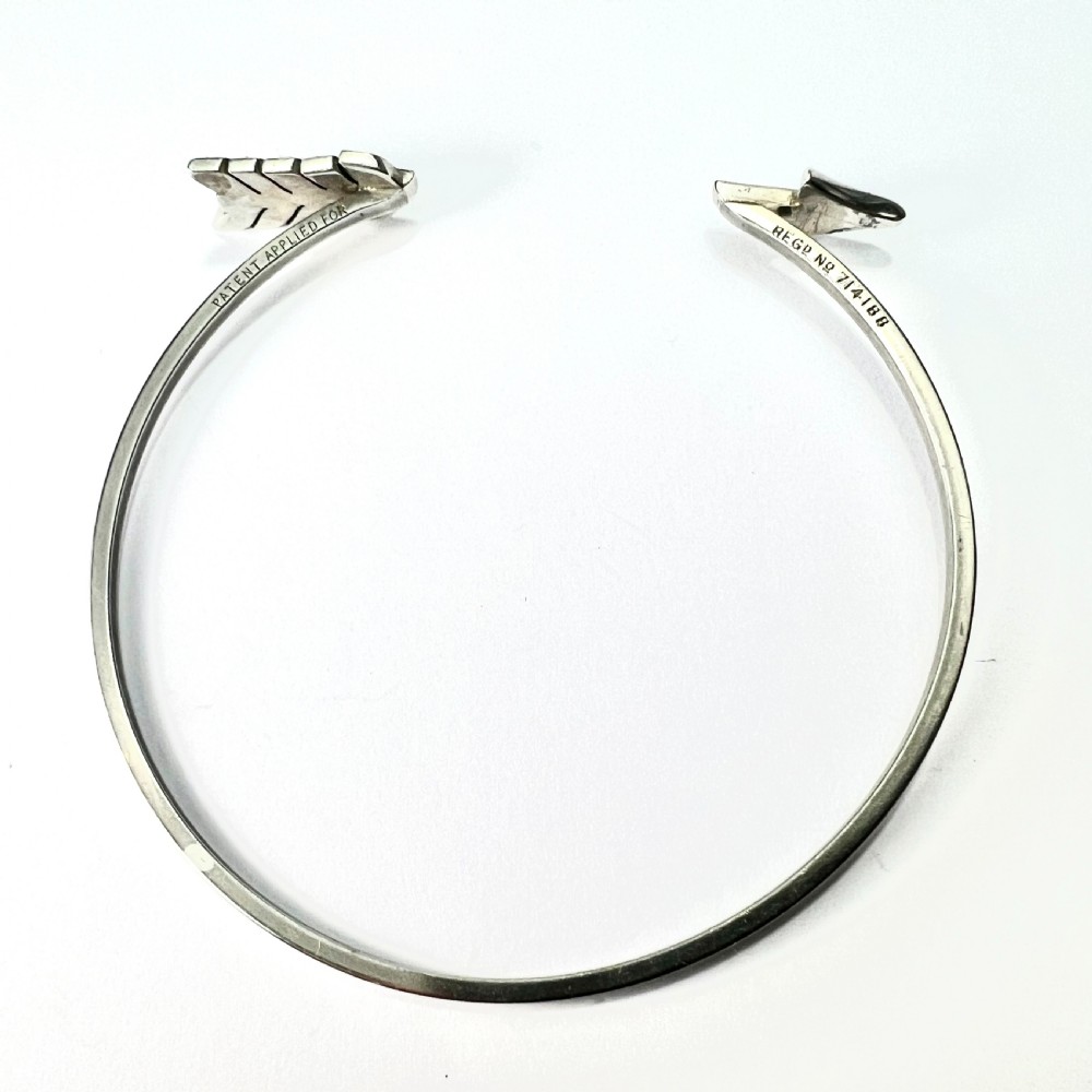 An open silver-toned metal cuff bangle designed in the shape of an arrow set with clear paste glass stones along the head and tail. View III