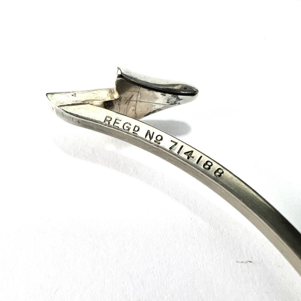 An open silver-toned metal cuff bangle designed in the shape of an arrow set with clear paste glass stones along the head and tail. View IV