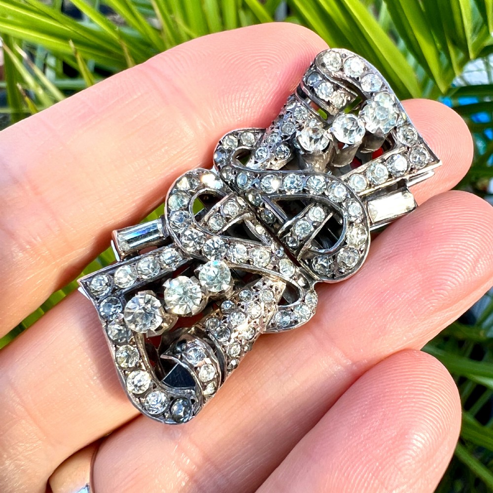 An Art Deco silver-tone paste duette brooch featuring geometric scrollwork set with round and baguette cut clear paste stones. View II