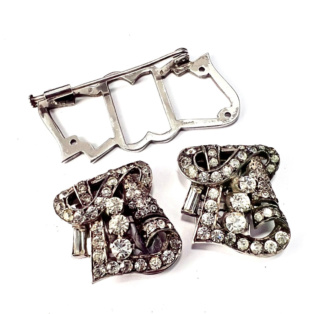An Art Deco silver-tone paste duette brooch featuring geometric scrollwork set with round and baguette cut clear paste stones. View III