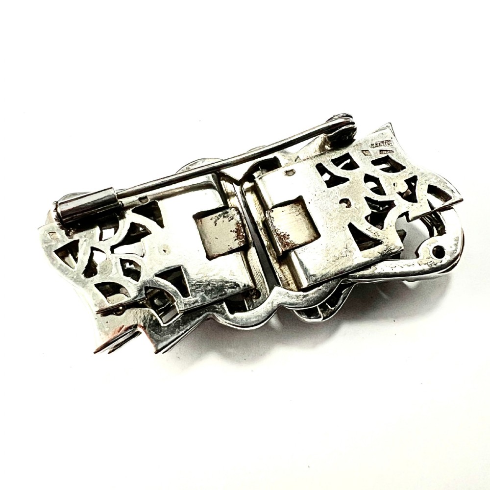 An Art Deco silver-tone paste duette brooch featuring geometric scrollwork set with round and baguette cut clear paste stones. View VI