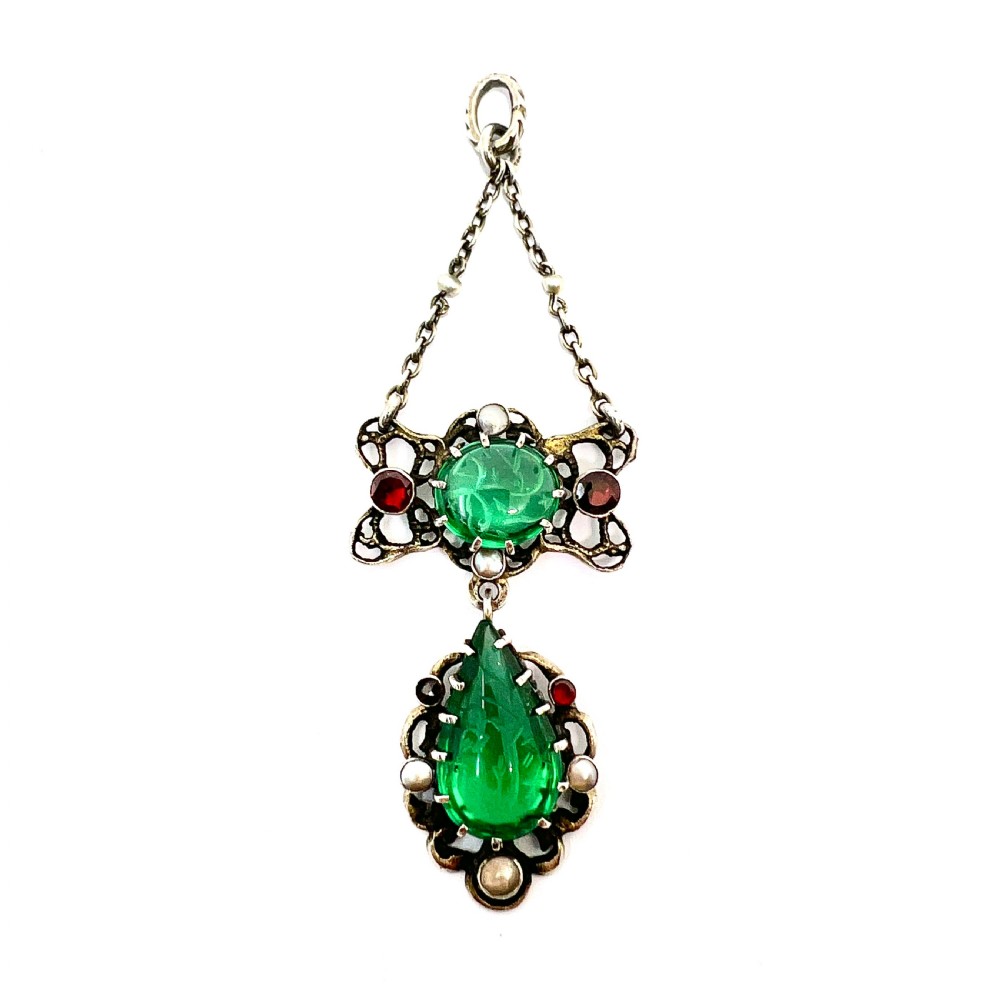 An antique silver pendant featuring carved green paste stones, round garnets, and seed pearls set in an openwork filigree frame. View II