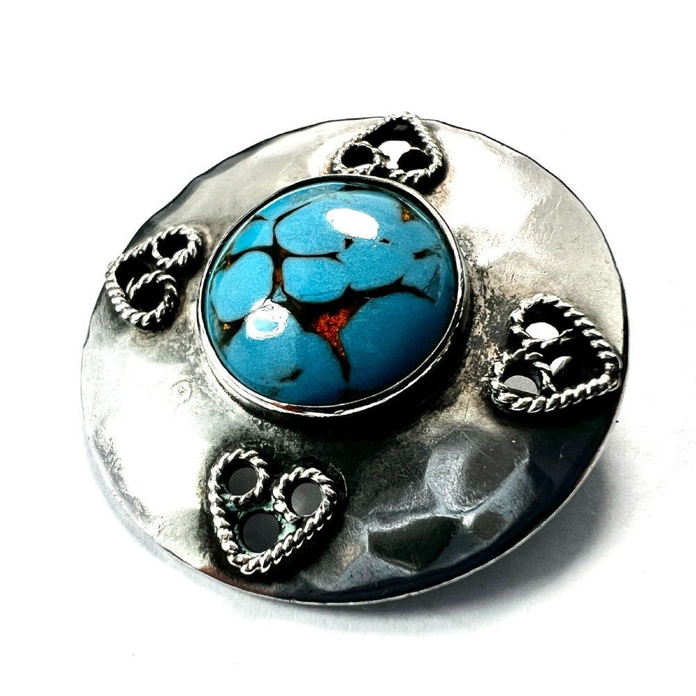 A circular hand-hammered silver brooch featuring a central turquoise glass cabochon framed by four rope-twist heart motifs. View II
