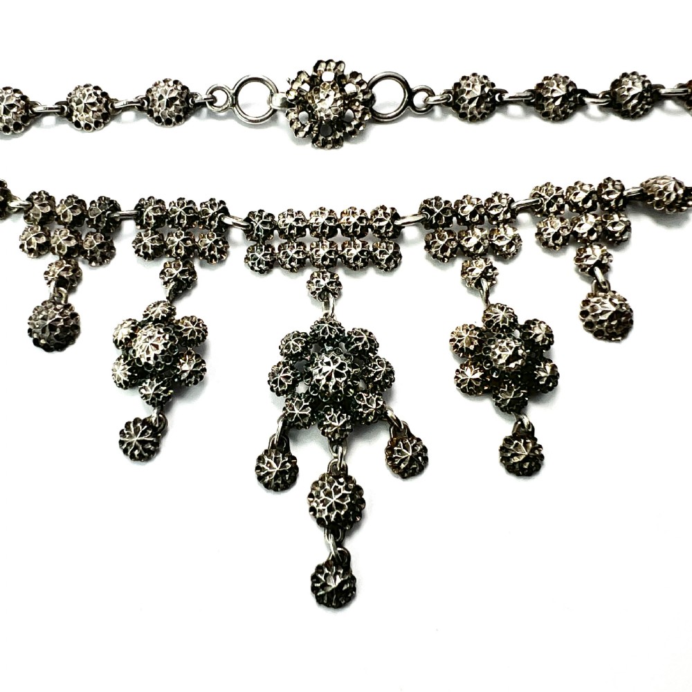 Victorian sterling silver necklace featuring textured spherical links and suspended chandelier drop motifs against a white backdrop. View II