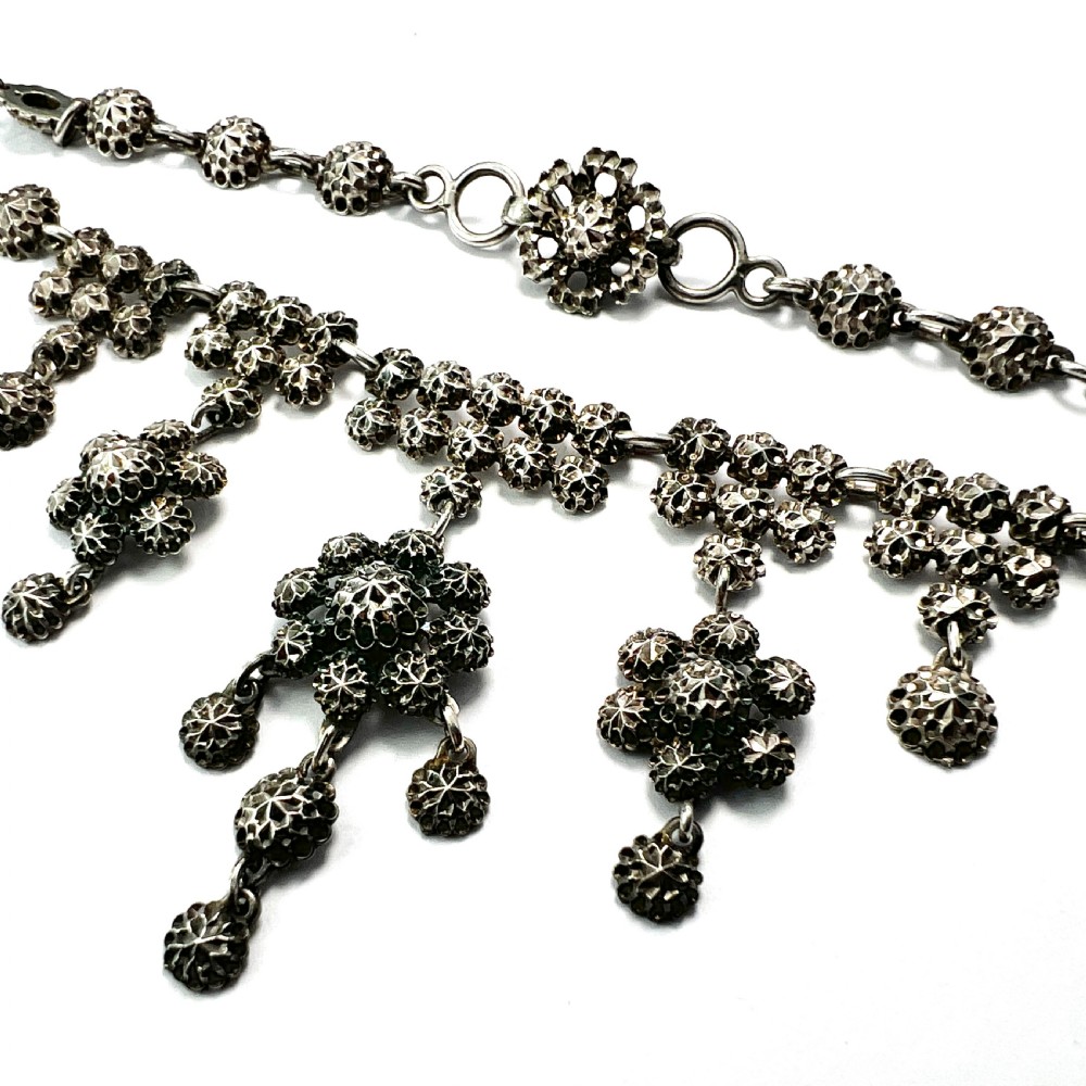 Victorian sterling silver necklace featuring textured spherical links and suspended chandelier drop motifs against a white backdrop. View VII