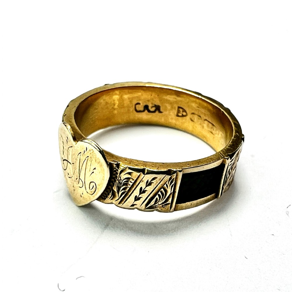 An Edwardian yellow gold ring featuring a central heart motif engraved with a monogram and shoulders decorated with chased scroll patterns. View V