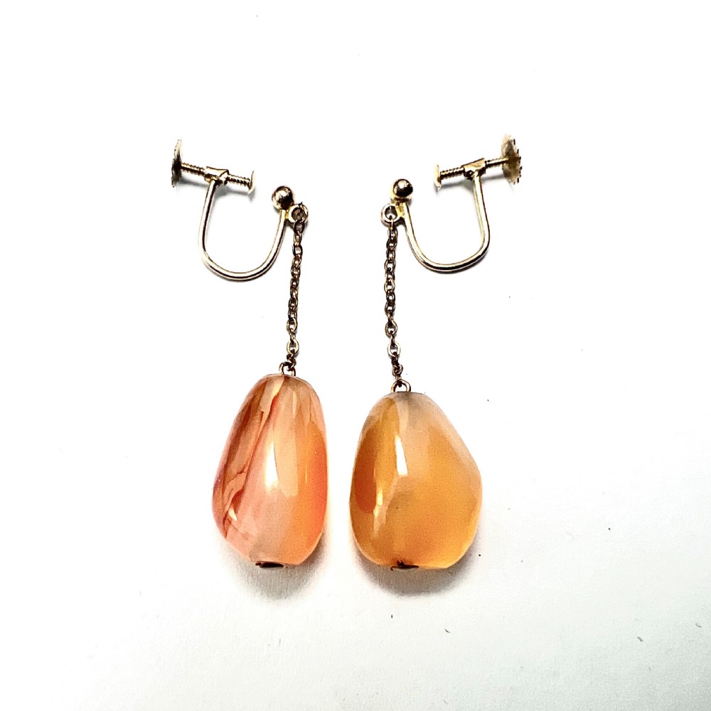 A pair of antique nine-carat gold screwback earrings featuring fine chain links suspending polished orange-toned agate teardrops.