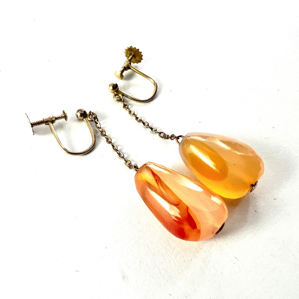 A pair of antique nine-carat gold screwback earrings featuring fine chain links suspending polished orange-toned agate teardrops. View III