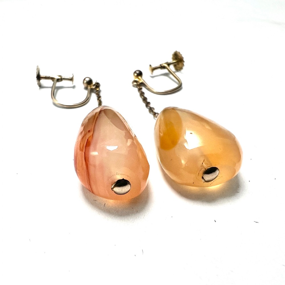 A pair of antique nine-carat gold screwback earrings featuring fine chain links suspending polished orange-toned agate teardrops. View V