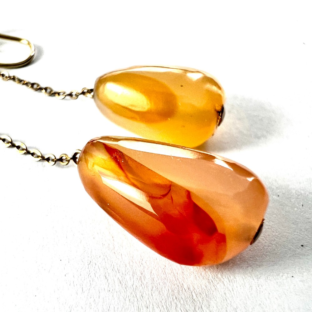 A pair of antique nine-carat gold screwback earrings featuring fine chain links suspending polished orange-toned agate teardrops. View VI