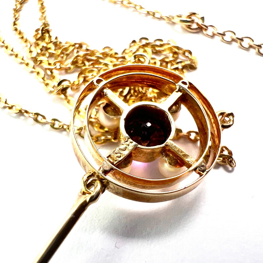 An Edwardian 15ct gold chain necklace featuring a circular pendant set with a round amethyst and four pearls, with a linear drop holding a seed pearl and an oval facet-cut amethyst. View VI