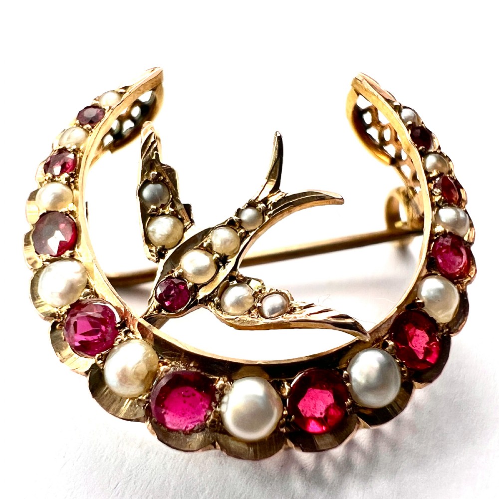 A 9ct gold crescent moon brooch set with alternating rubies and seed pearls surrounding a central swallow motif embellished with pearls and a ruby eye. View III