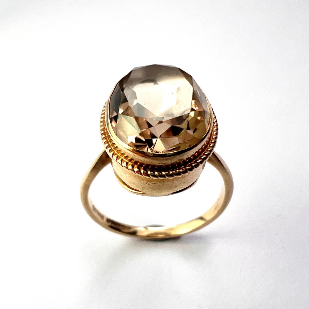 A vintage yellow gold ring set with a large oval faceted translucent brown smoky quartz stone framed by a twisted rope bezel detail. View V