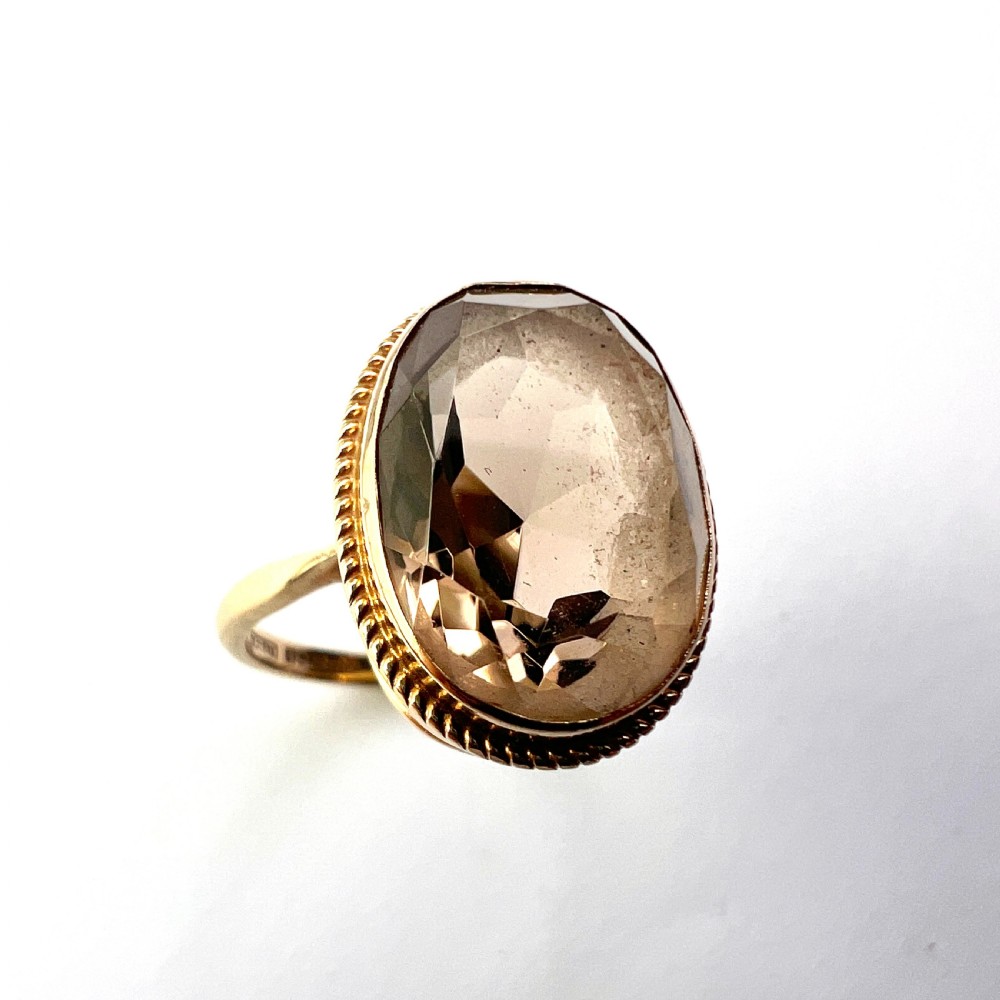 A vintage yellow gold ring set with a large oval faceted translucent brown smoky quartz stone framed by a twisted rope bezel detail. View VI