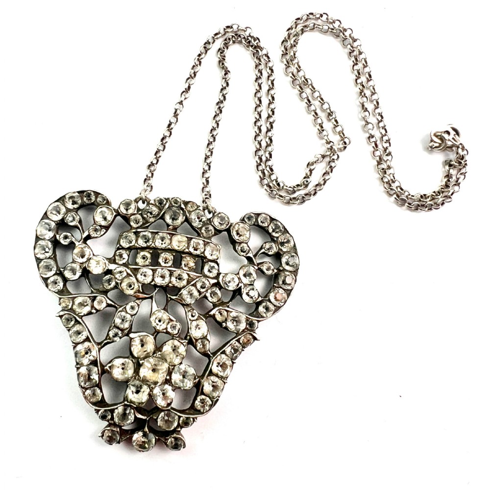 An intricate openwork Georgian silver pendant set with faceted clear black dot paste stones on a silver chain.