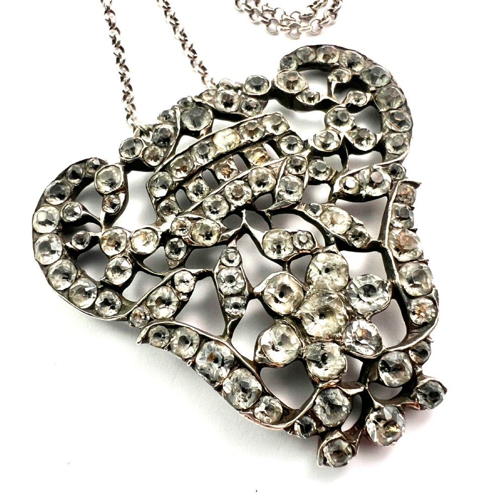 An intricate openwork Georgian silver pendant set with faceted clear black dot paste stones on a silver chain. View II