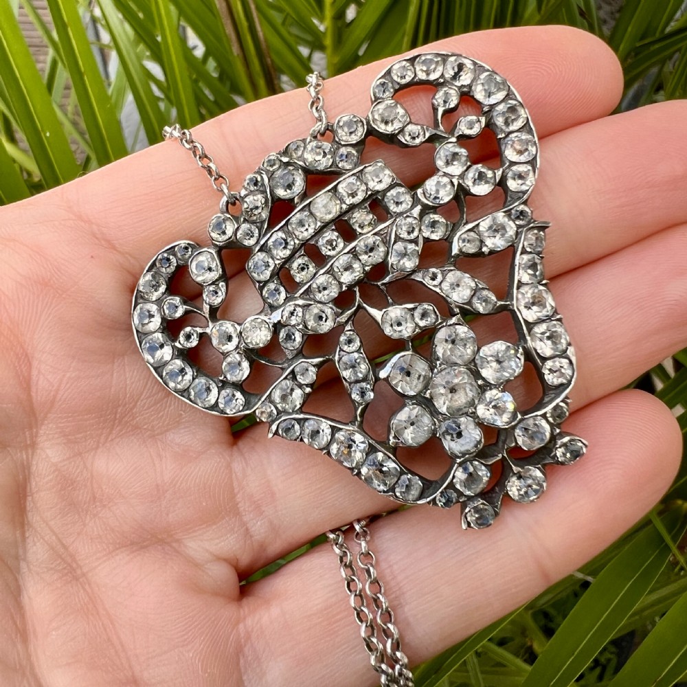 An intricate openwork Georgian silver pendant set with faceted clear black dot paste stones on a silver chain. View VIII