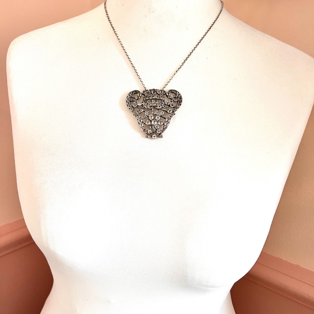 An intricate openwork Georgian silver pendant set with faceted clear black dot paste stones on a silver chain. View IX
