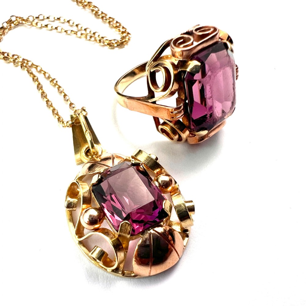 A 1940s Retro 14ct gold cocktail ring featuring a large rectangular cut purple paste gemstone set within ornate metal scrollwork. View IX