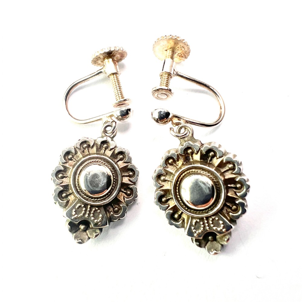 A pair of silver Victorian Aesthetic Era drop earrings featuring a sunburst motif with beaded detailing and screwback fastenings.